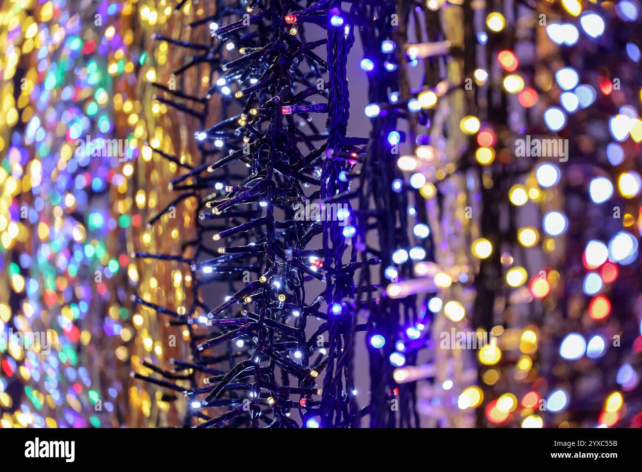 Weihnachtslichter an elektrischen Girlanden in einem Geschäft. Neujahrsdekoration in verschiedenen Farben Stockfoto