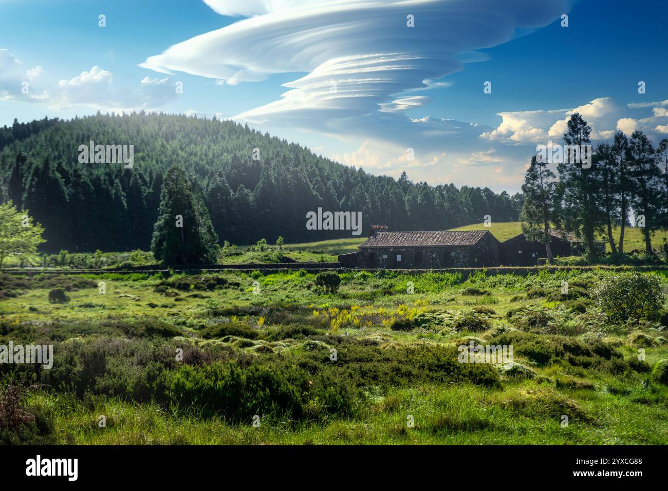Wunderschöner Panoramablick auf üppig grüne Wiesen, Steinbauten und dramatischen bewölkten Himmel, Terceira, Azoren Stockfoto