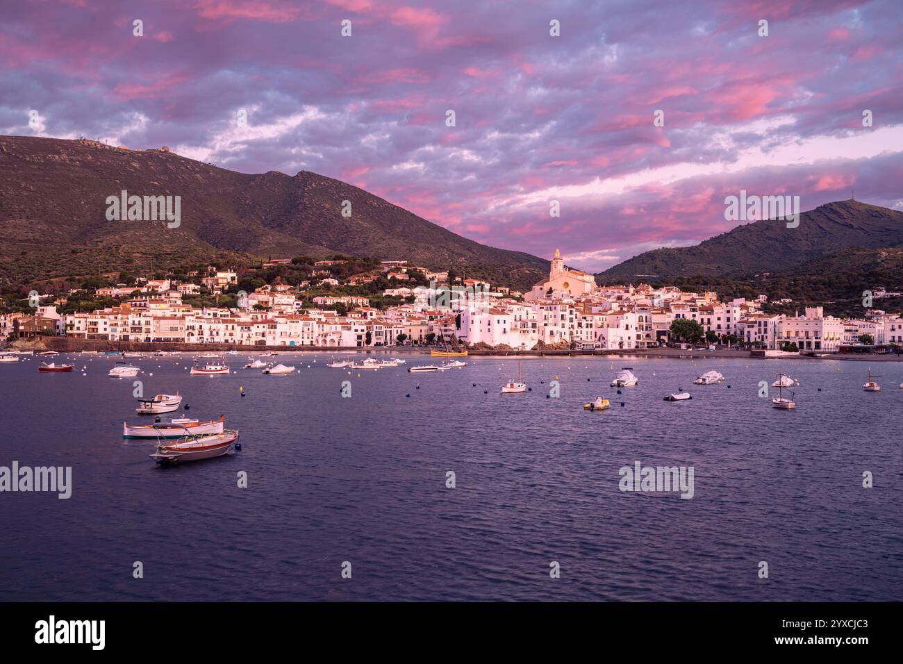 Heller Sonnenaufgang mit violetten Wolken über der Bucht und der Altstadt von Cadaqués, Katalonien, Spanien Stockfoto