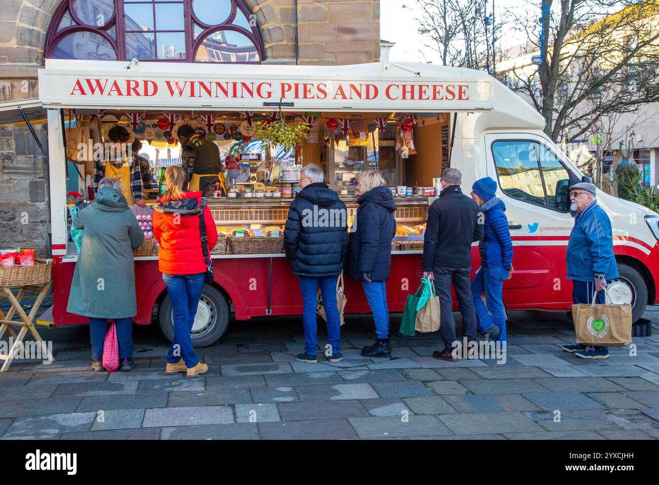 Auf dem weihnachtsmarkt in Warwick, England, stehen Leute in einem Geschäft für mobile Transporter, die preisgekrönte Kuchen und Käse verkaufen Stockfoto