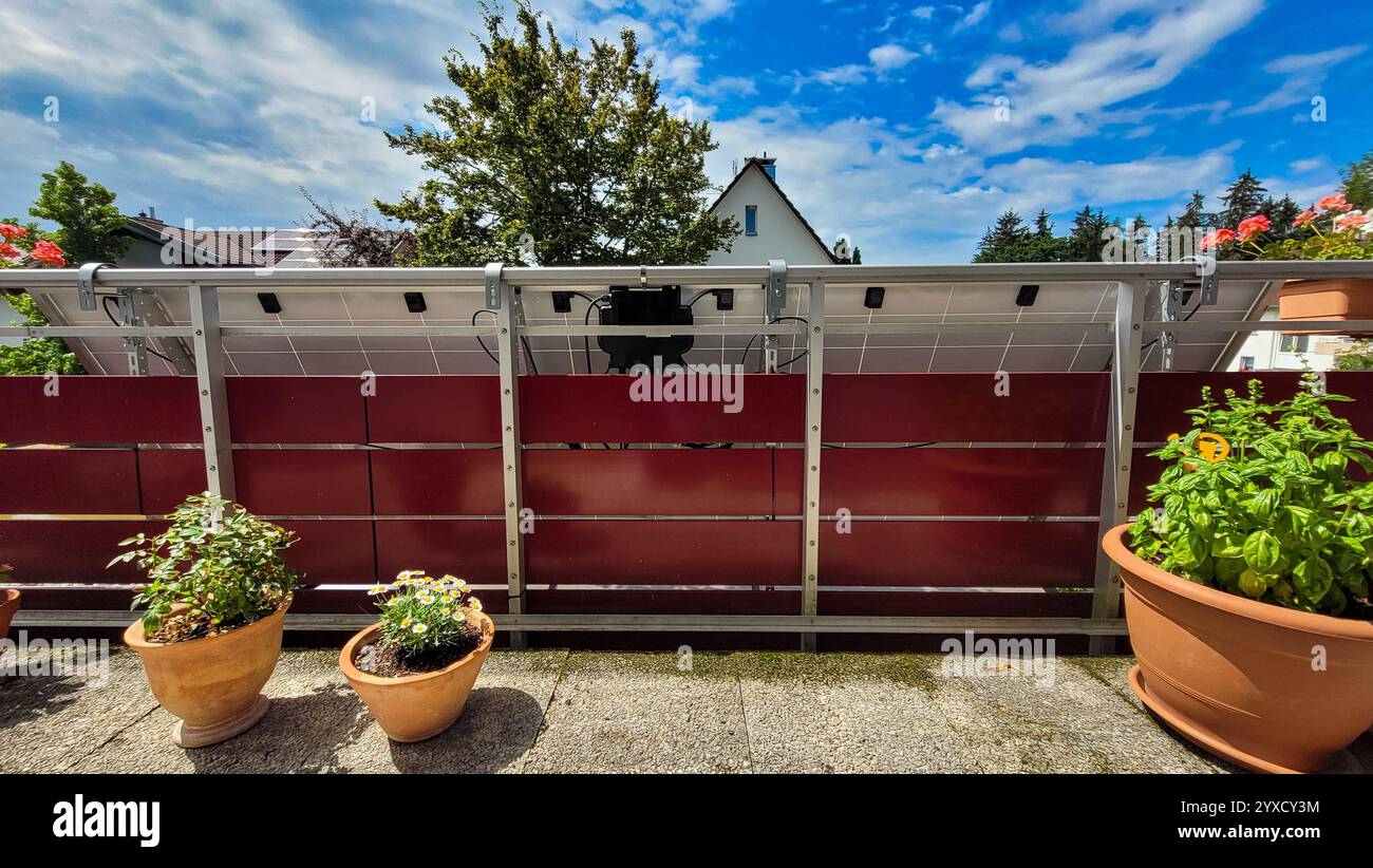 Installation einer Balkonsolaranlage, Innenansicht, fixiert in einem Winkel von 30 Grad auf dem roten Balkon eines Wohnhauses, umgeben von Töpfen mit Stockfoto