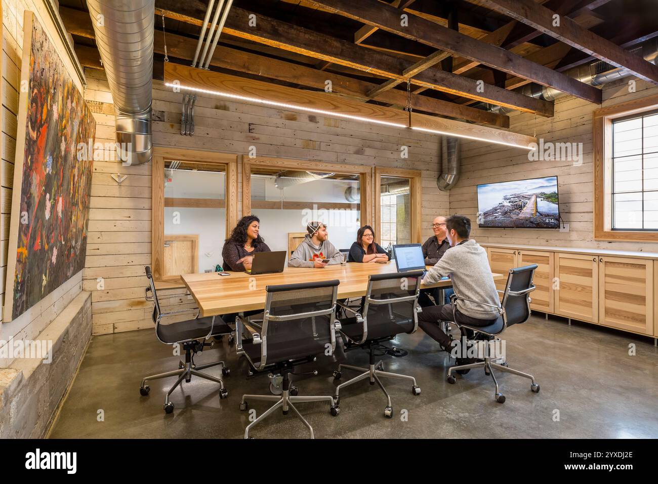 Gäste, die sich im Konferenzraum mit Konferenztisch und Holzvertäfelung unterhalten Stockfoto