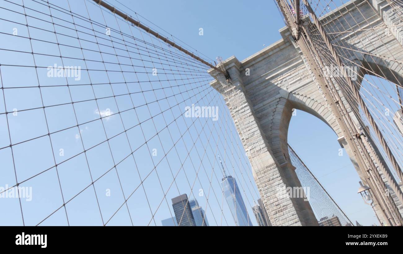 Brooklyn Bridge nach Manhattan, Kabel und blauer Himmel. Symbol New York City, Reiseziel USA. Architektur der Vereinigten Staaten von Amerika, touristisches Wahrzeichen. Kabelbrücke. Niederländischer Winkel. Stockfoto