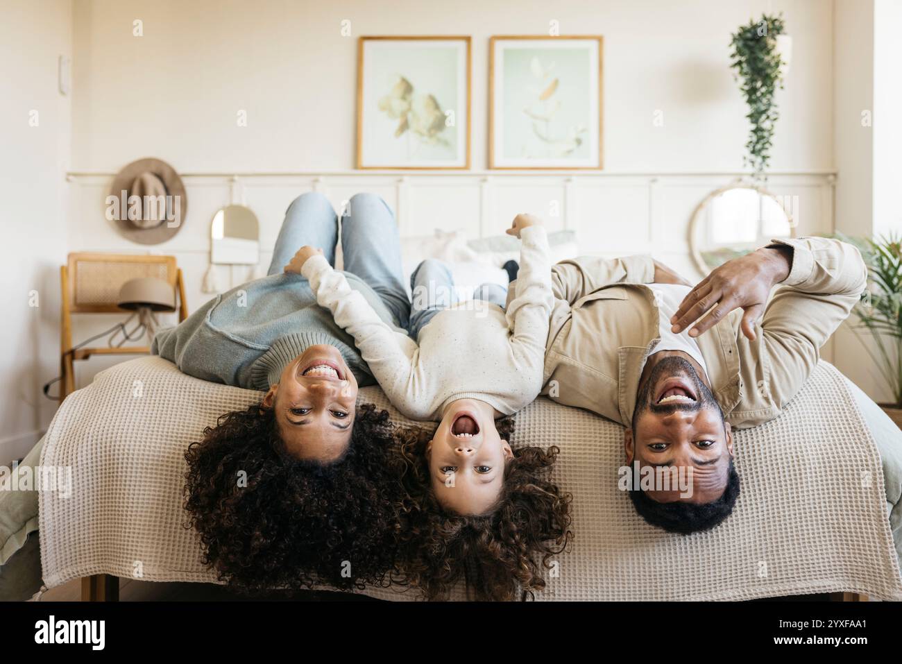 Eine Familie genießt einen freudigen Moment zu Hause, indem sie lacht und auf einem Bett spielt und eine positive Familienbindung und Glück zeigt. Stockfoto