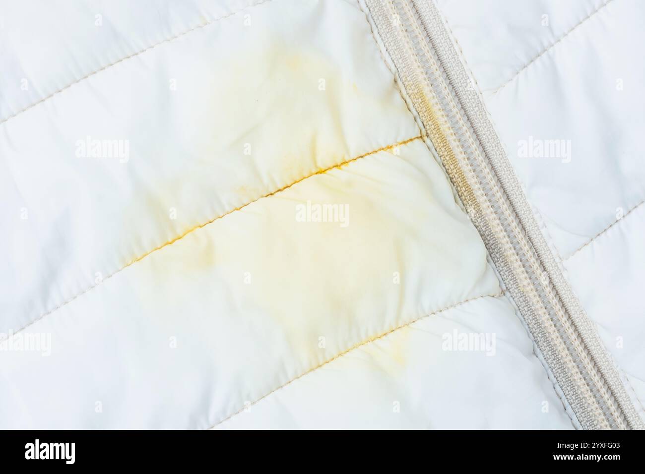 Nahaufnahme von schmutzigem gelben Soßenfleck auf Oberbekleidung. Das Konzept der Entfernung von Alltagsflecken auf Kleidung. Draufsicht. Hochwertige Fotos Stockfoto