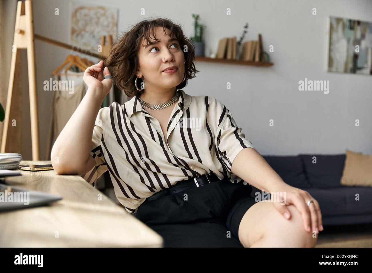 Die Frau mit lockigen Haaren entspannt sich in ihrer modernen Wohnung und zeigt ihren stilvollen und lebendigen Lebensstil. Stockfoto