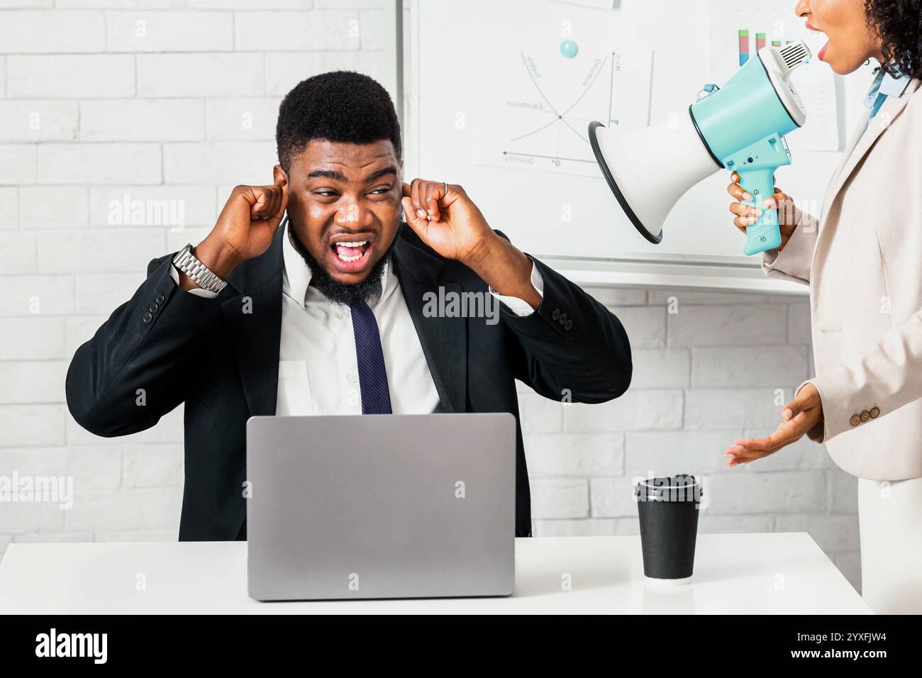 Erzürnte weibliche Chefin mit Lautsprechern, die ihren verängstigten Untergebenen anschreien Im Büro des Unternehmens Stockfoto