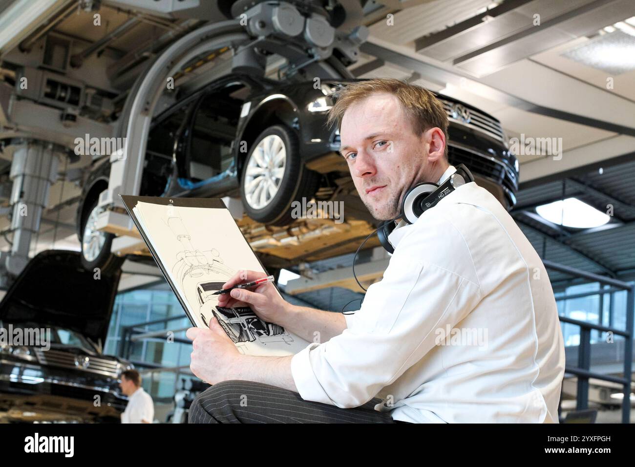 14.03.2011, Deutschland, Sachsen, Dresden, auf dem Foto Illustrator und Comic Zeichner Matthias Seifert, hier beim Skizzieren vom Werdegang eines VW-Phaetons in der Gläsernen Manufaktur von Volkswagen auf dem Straßburger Platz fotografiert *** 14 03 2011, Germany, Sachsen, Dresden, im Foto-Illustrator und Comic-Künstler Matthias Seifert, hier fotografiert, der die Entwicklung eines VW Phaeton in Volkswagens Transparent Factory am Strassburger Platz skizziert Stockfoto