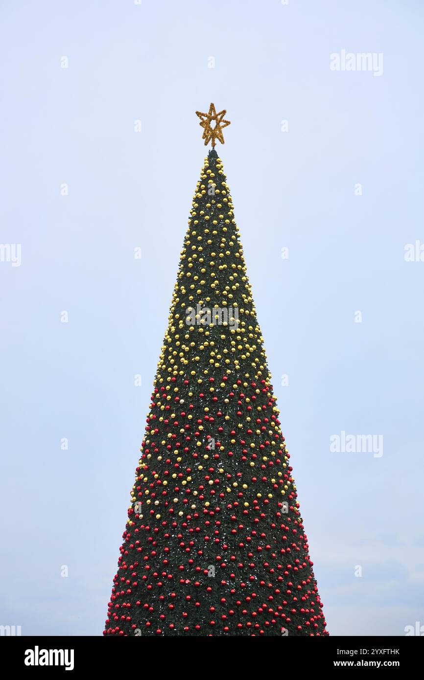 Weihnachtsbaum mit einem Stern auf der Spitze, dekoriert mit gelben und roten Kugeln und Girlanden. Der wichtigste Neujahrsbaum Kirgisistans. Bischkek, Ala-Too Square. Aus Stockfoto