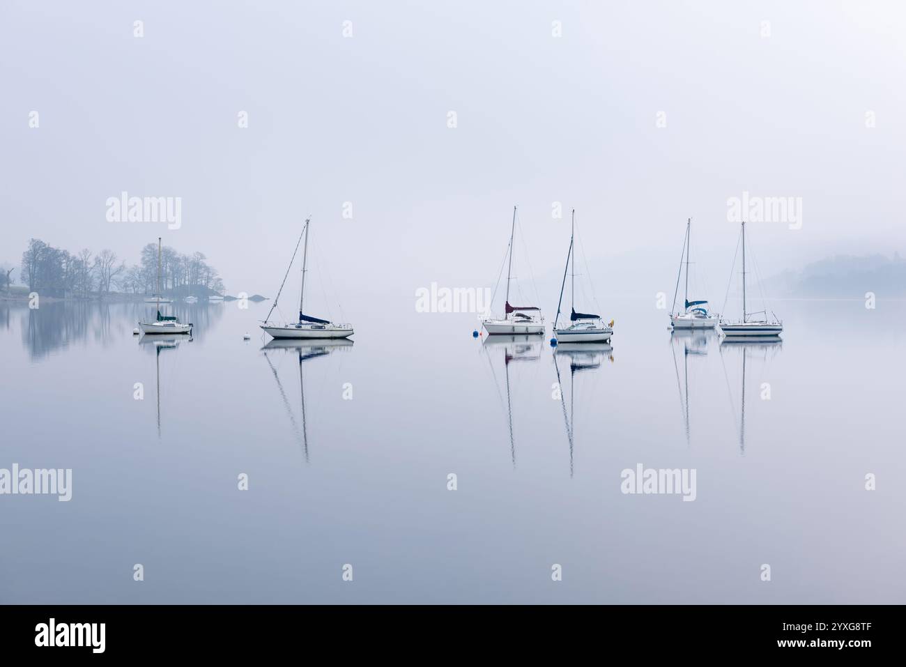 Bootsreihe mit ruhigen Reflexen im Wasser in Waterhead, Windermere, Lake District, Großbritannien. Stockfoto