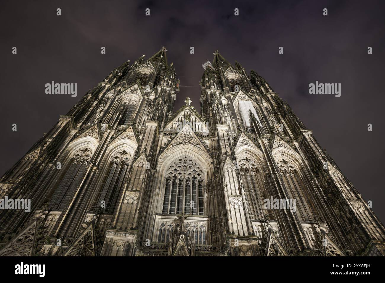 Kölner Dom, ein beeindruckender gotischer Dom, beleuchtet bei Nacht und fotografiert vor dem bewölkten Himmel, Köln, Nordrhein-Westfalen, Keim Stockfoto