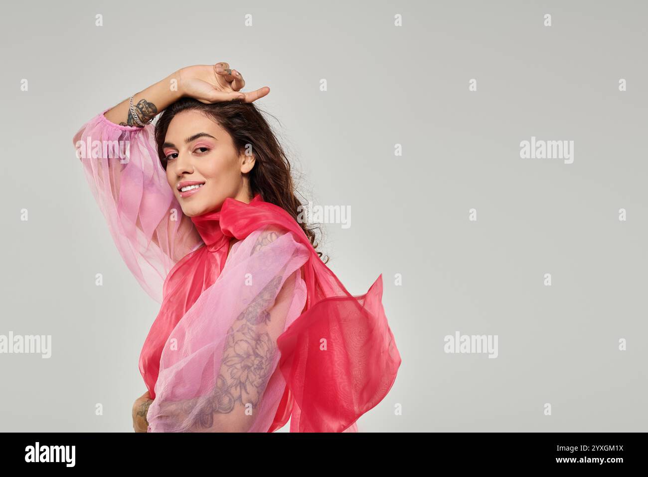 Eine junge, schöne Frau zeigt ihre verspielte Seite, während sie ein farbenfrohes Outfit in einem Studio trägt. Stockfoto