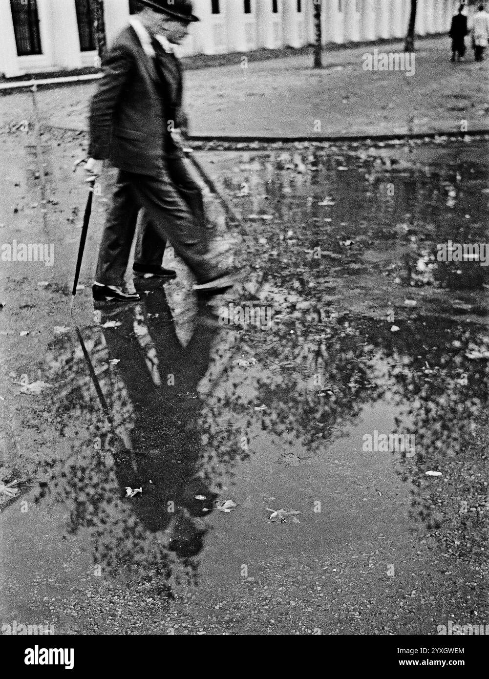 Zwei Herren mit Bowlerhut streiften auf ihrem Weg zur Arbeit durch Pfützen, London, 1950er Jahre Stockfoto