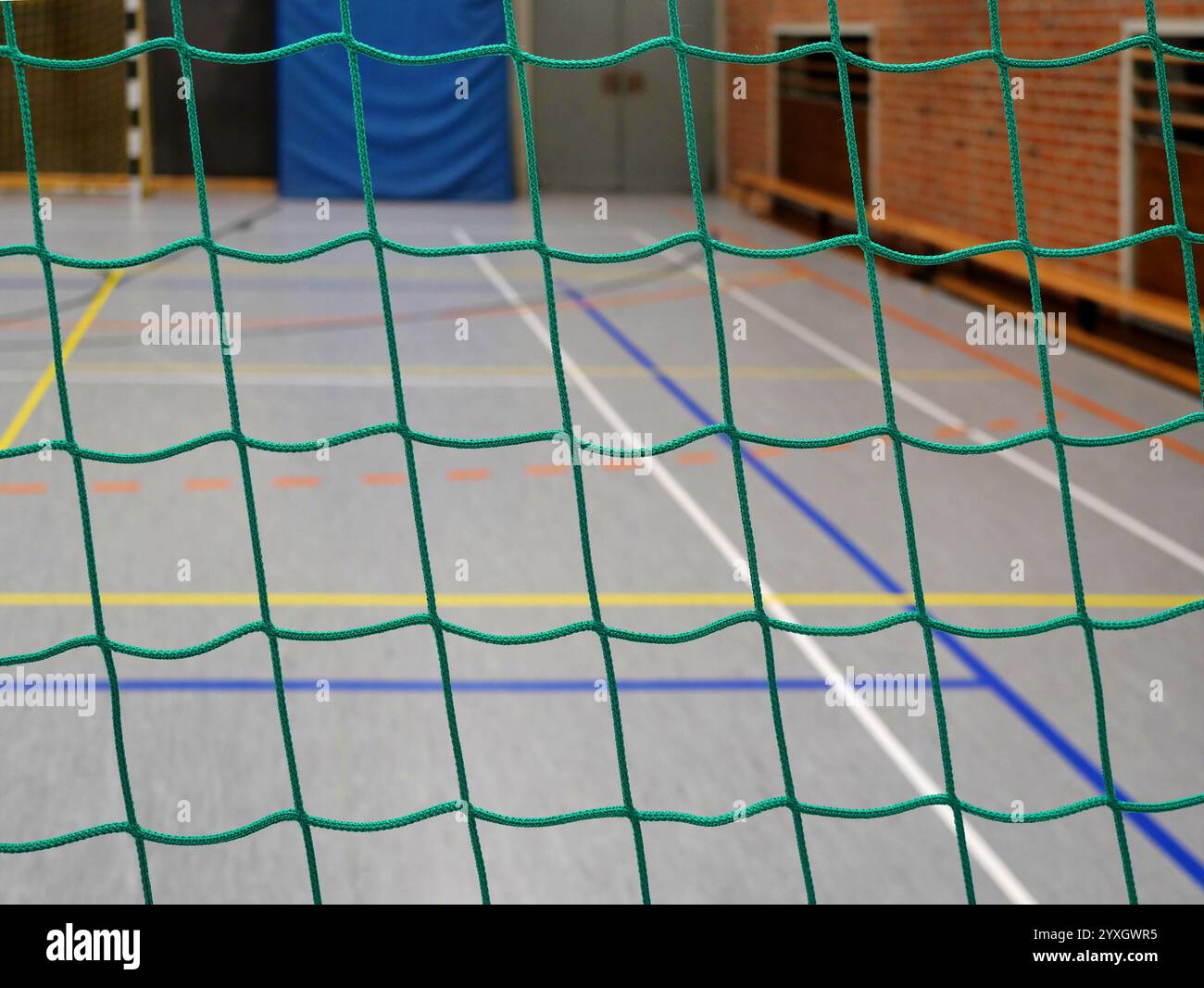 Ballschutznetz in einer Sporthalle: Das grüne, grobmaschige Netz dient zur Bereichsabtrennung und Sicherheit. Stockfoto