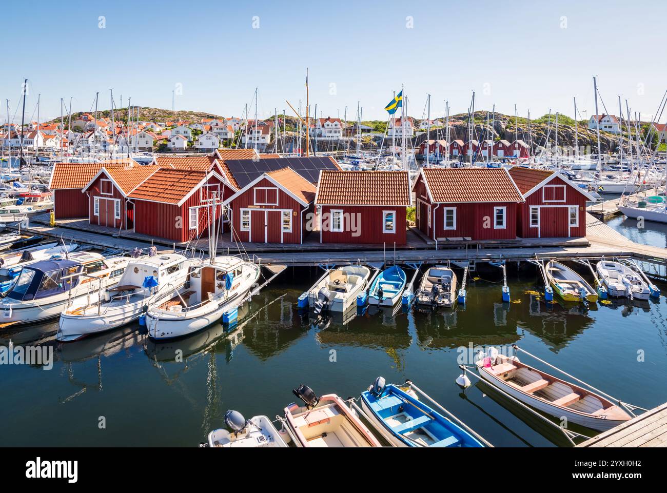 Blick auf den Gästehafen in Skärhamn, Schweden, ein beliebter Yachthafen in der Touristenprovinz Bohuslän, mit typischen roten Hütten umgeben von Festbooten. Stockfoto