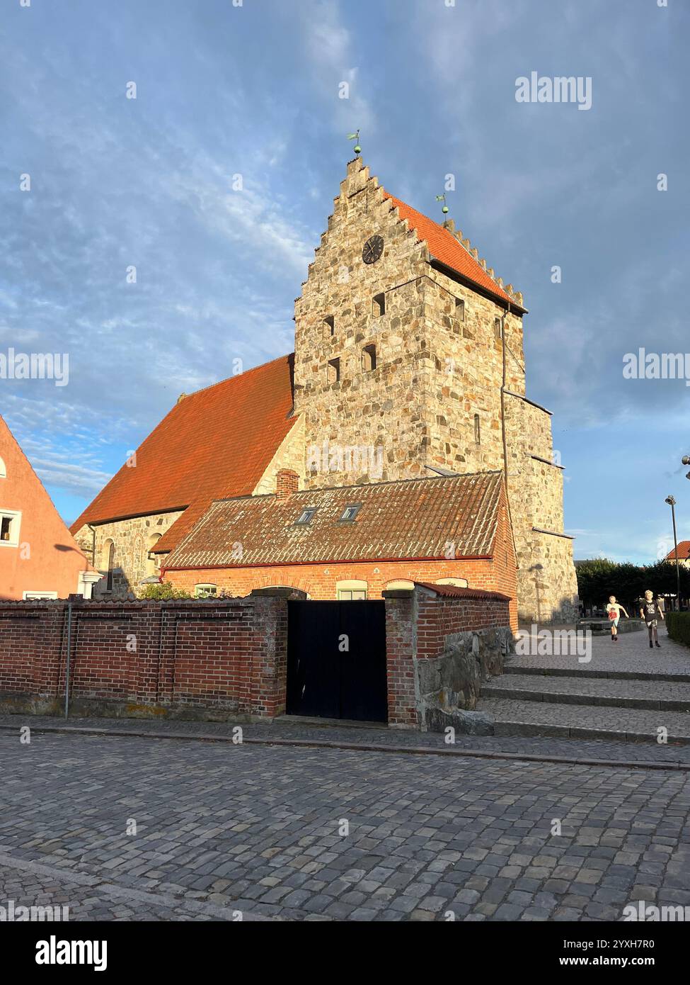 Kirche Sankt Nicolai in Simrishamn, Schweden, beleuchtet von der Sonne und mit bewölktem und blauem Himmel im Hintergrund. Foto im Sommer 2023. Stockfoto