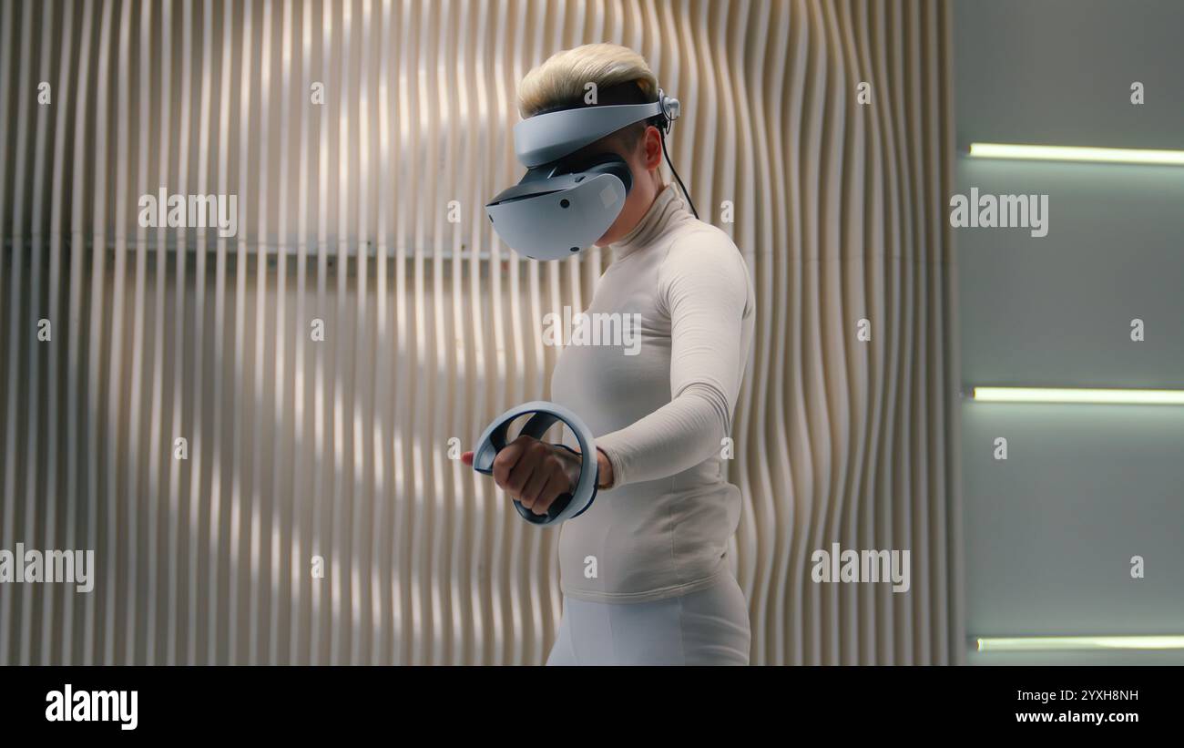 Weibliche Gamer Spieler Mädchen Spielsüchtige Frau in weiß Neon futuristische 3D Meta World VR Brille Helm AR Brille Cyber Virtual Reality Vision Stockfoto