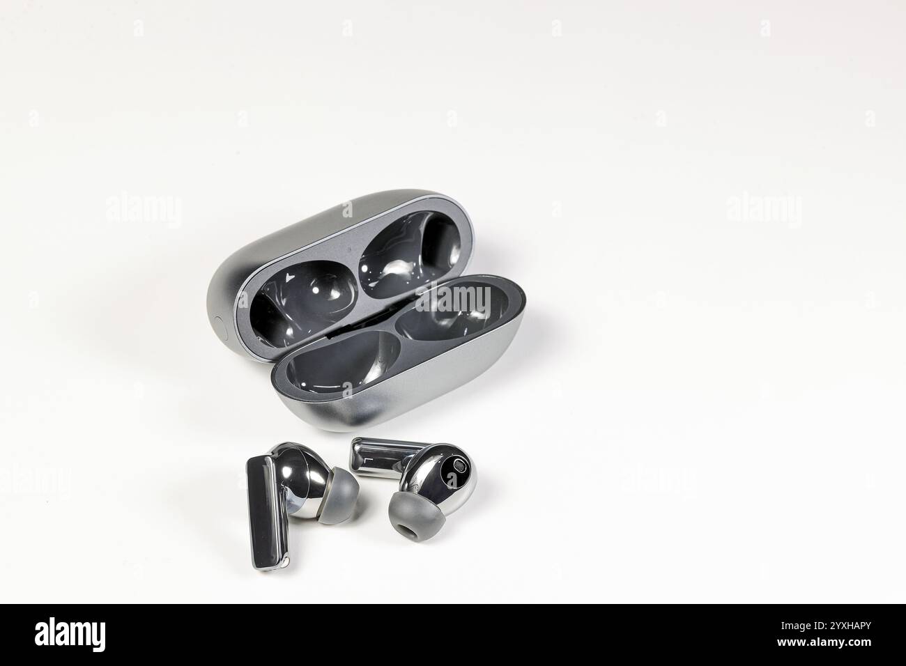 Luxuriöse Bluetooth-Kopfhörer oder -Ohrstöpsel oder Kopfhörer mit Ladetasche auf weißem Hintergrund. Stockfoto