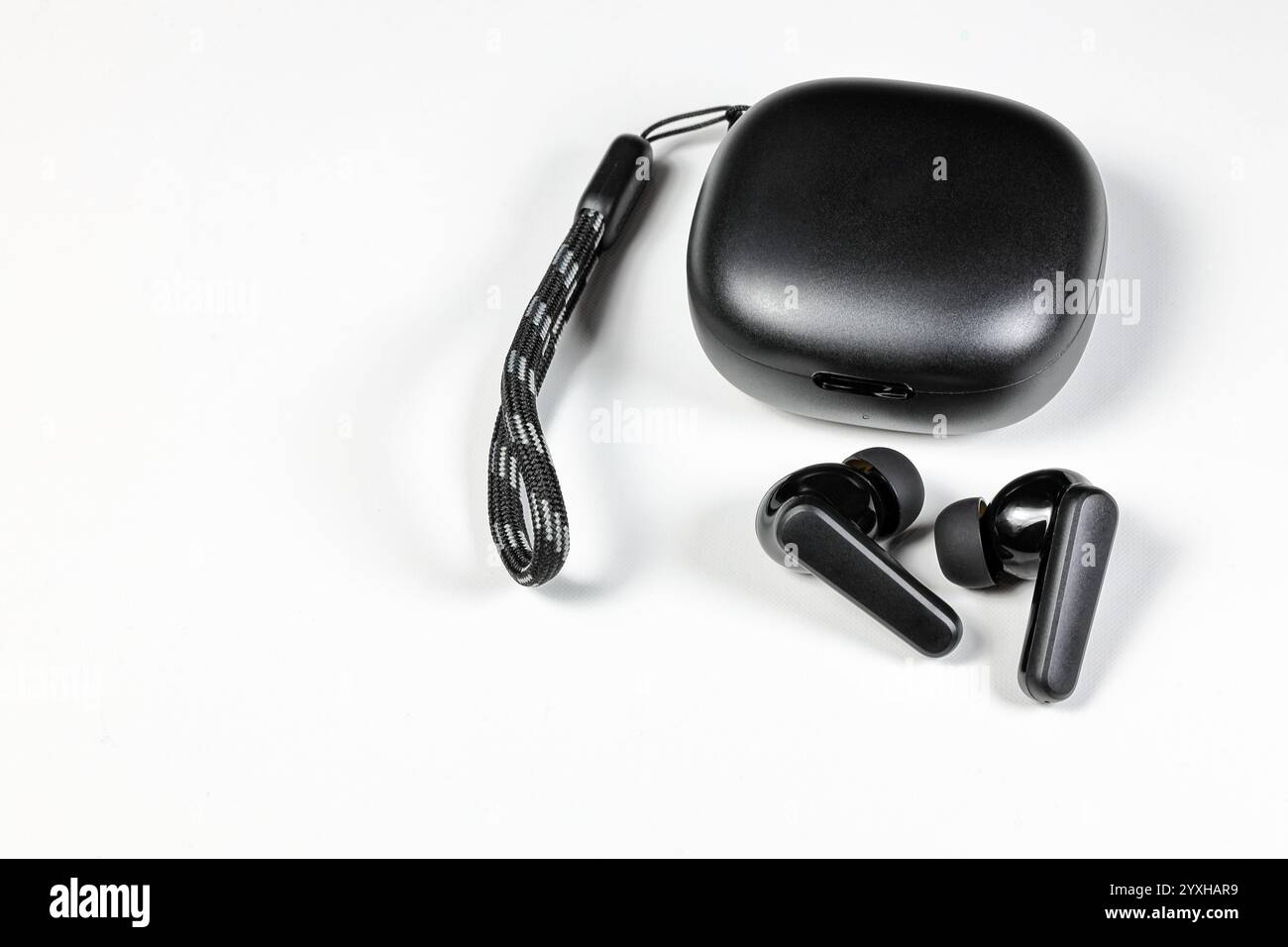 Kabelloser Bluetooth-Ohrhörer oder -Ohrhörer oder Kopfhörer mit Ladetasche auf weißem Hintergrund. Stockfoto