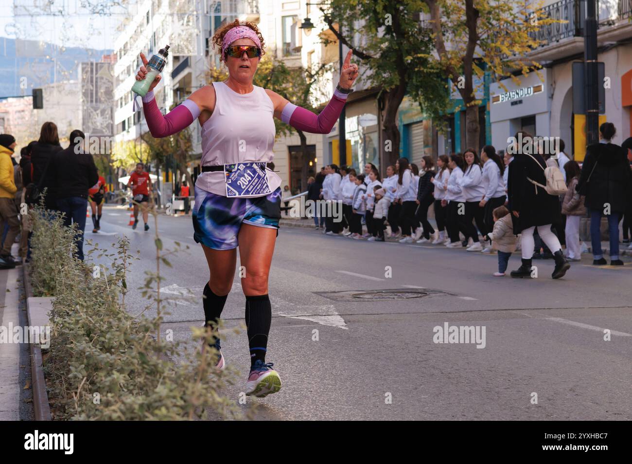 Ältere Frau beim Halbmarathon 2024 hebt die Arme für das Foto Stockfoto