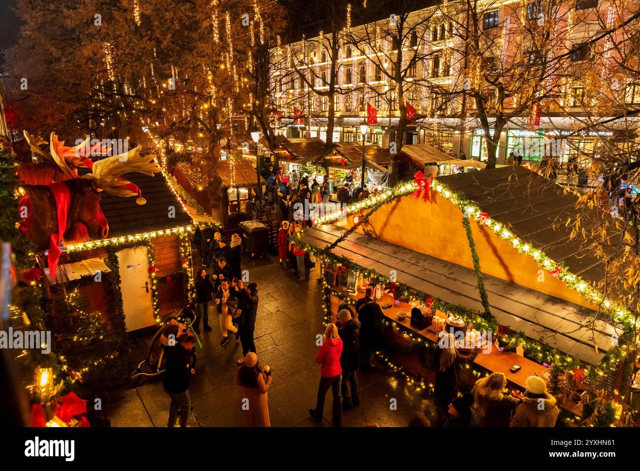 Nächtlicher Blick auf den belebten Weihnachtsmarkt in Oslo. Massen genießen die festlichen Lichter und die saisonale Atmosphäre im Stadtzentrum. Stockfoto