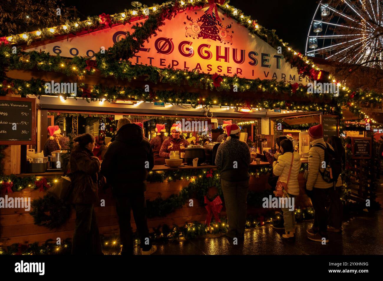 Kaufen Sie warme Getränke, einschließlich gløgg, auf dem Weihnachtsmarkt in Oslo. Der festliche Stand leuchtet nachts mit Weihnachtslichtern. Stockfoto