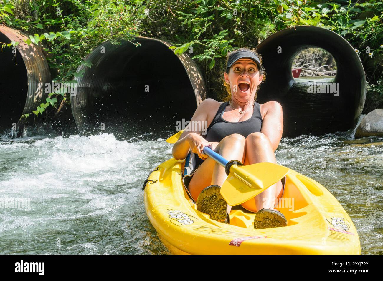 Eine Frau im mittleren Erwachsenenalter, die durch einen Düker Kajak fährt Stockfoto
