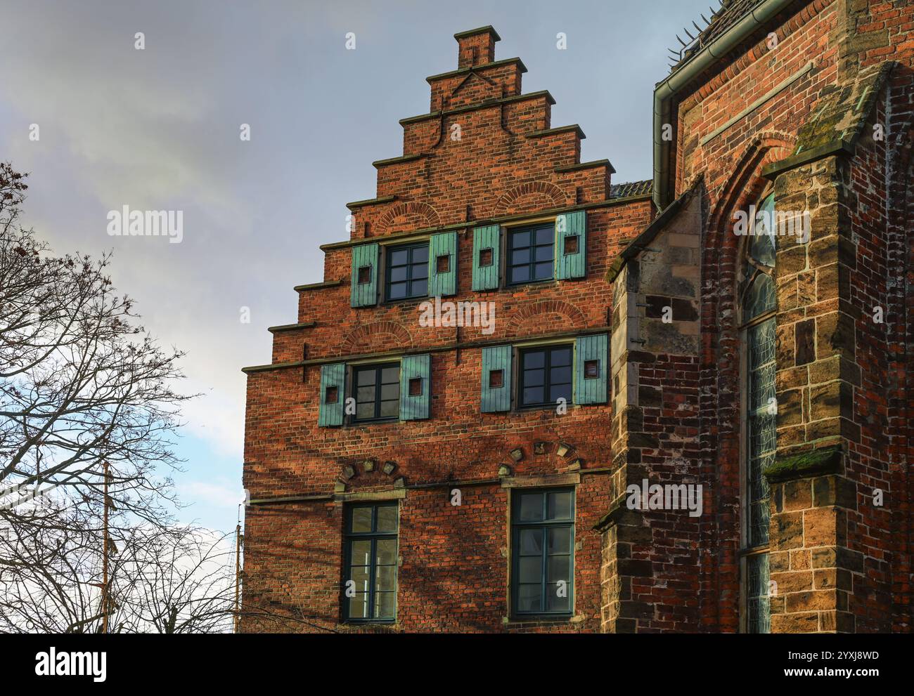 Historisches Gebäude an der Martini-Kirche in Bremen in roter Backsteinarchitektur mit Stufengiebel und Holzläden, bewölkter Himmel, ausgewählter Fokus Stockfoto