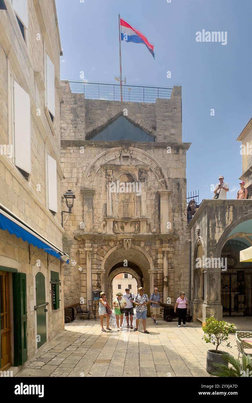 Korcula, Kroatien - 30. Juni 2024: Südliches Stadttor mit Touristen und Flagge, aus dem Inneren der Stadt gesehen Stockfoto