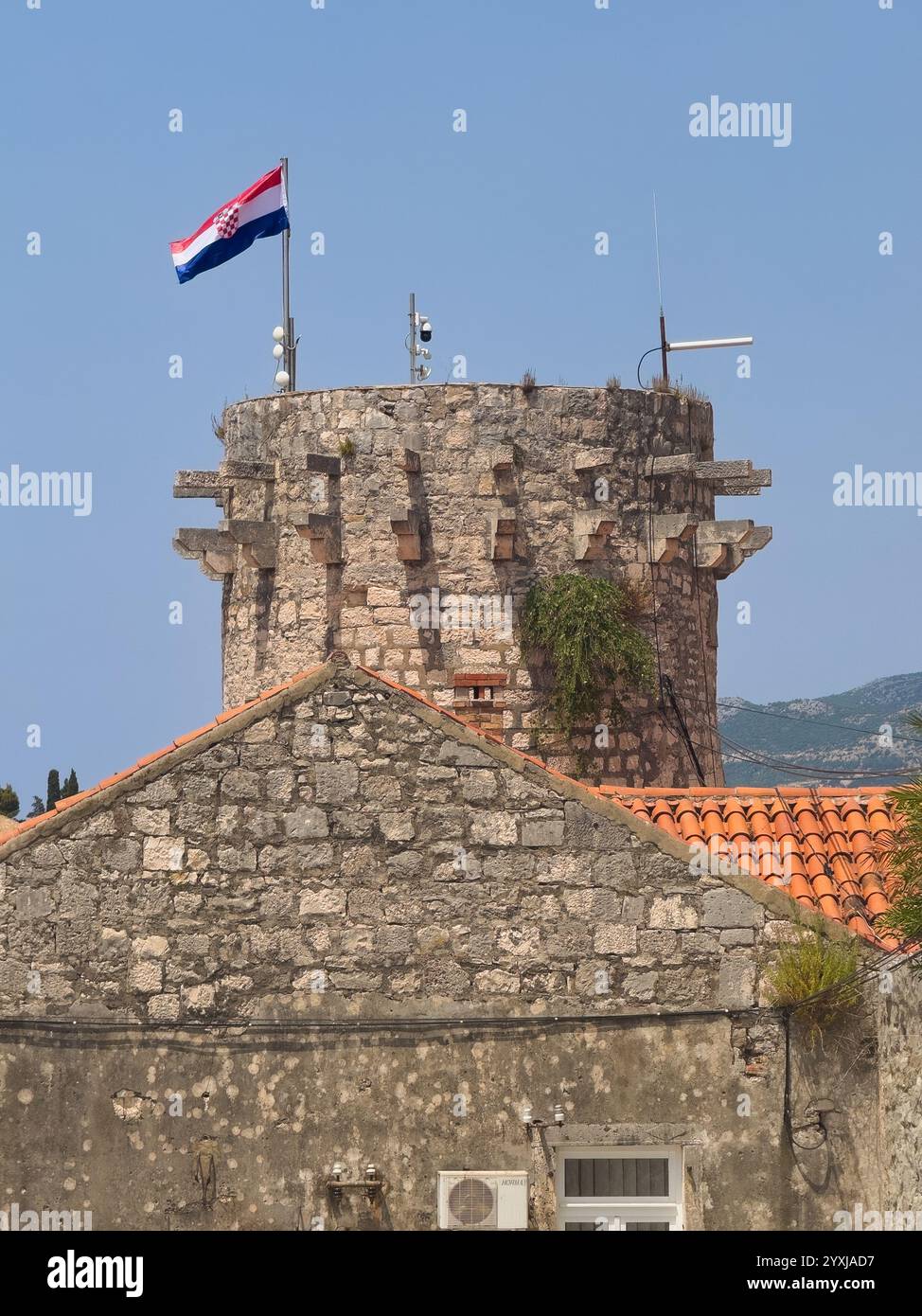 Korcula, Kroatien - 30. Juni 2024: Südlicher Stadttor mit Flagge oben, von Westmauern unter blauem Himmel aus gesehen Stockfoto