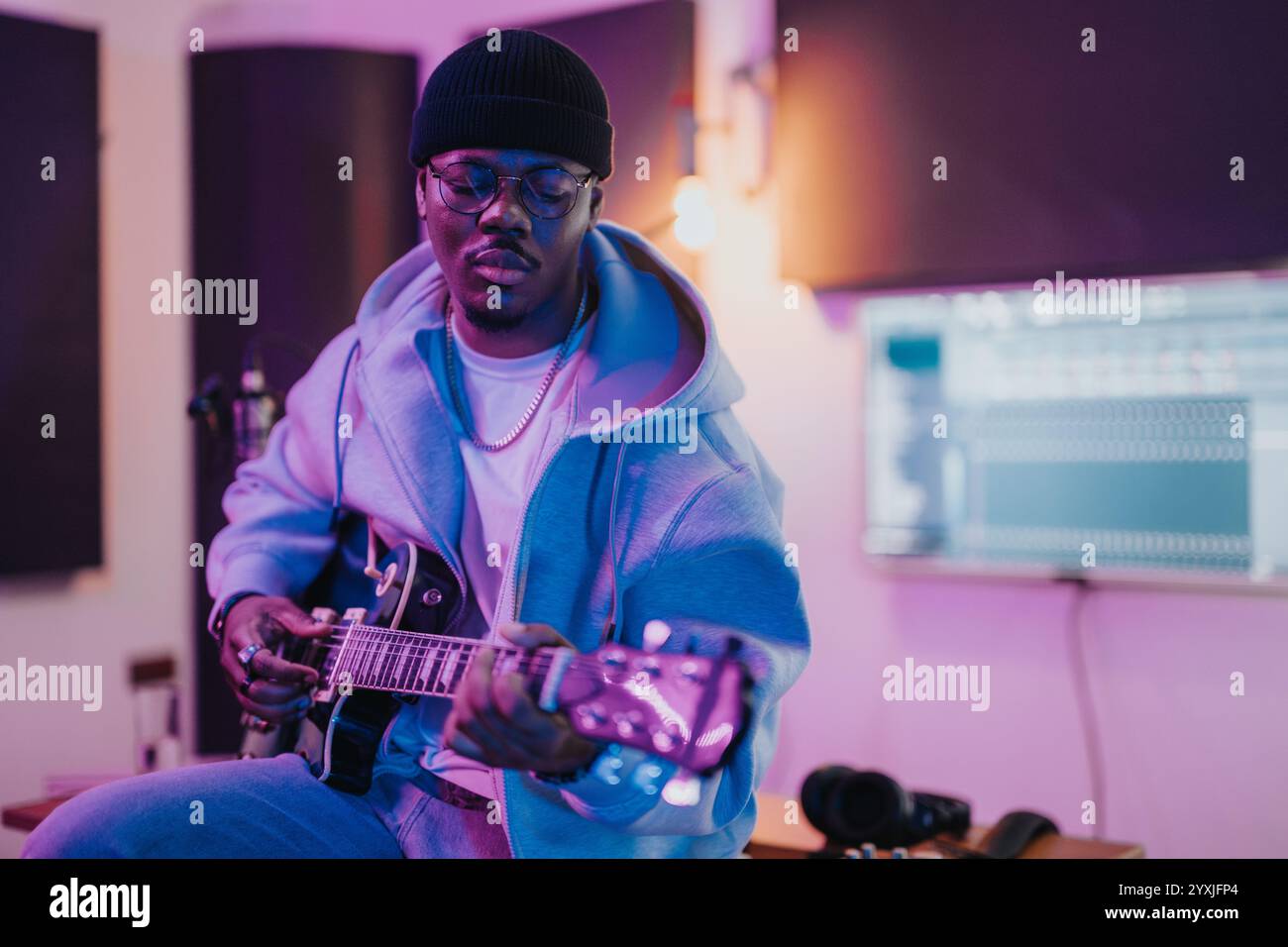 Musiker, der Musik in einem Aufnahmestudio mit elektrischer Gitarre und Ausrüstung kreiert Stockfoto
