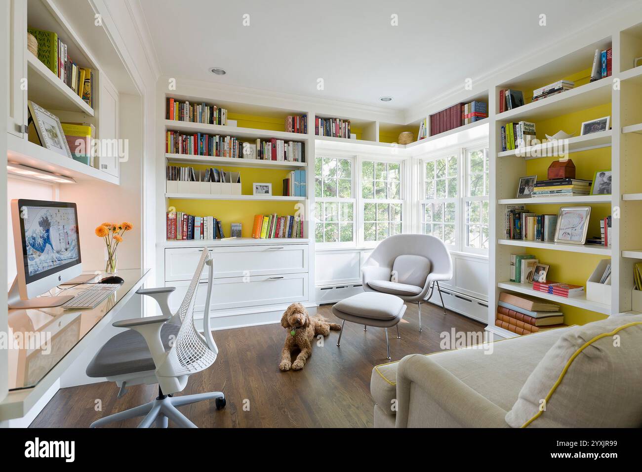 Helles, sonniges, weißes und gelbes Home Office mit Hund, der auf dem Boden liegt Stockfoto