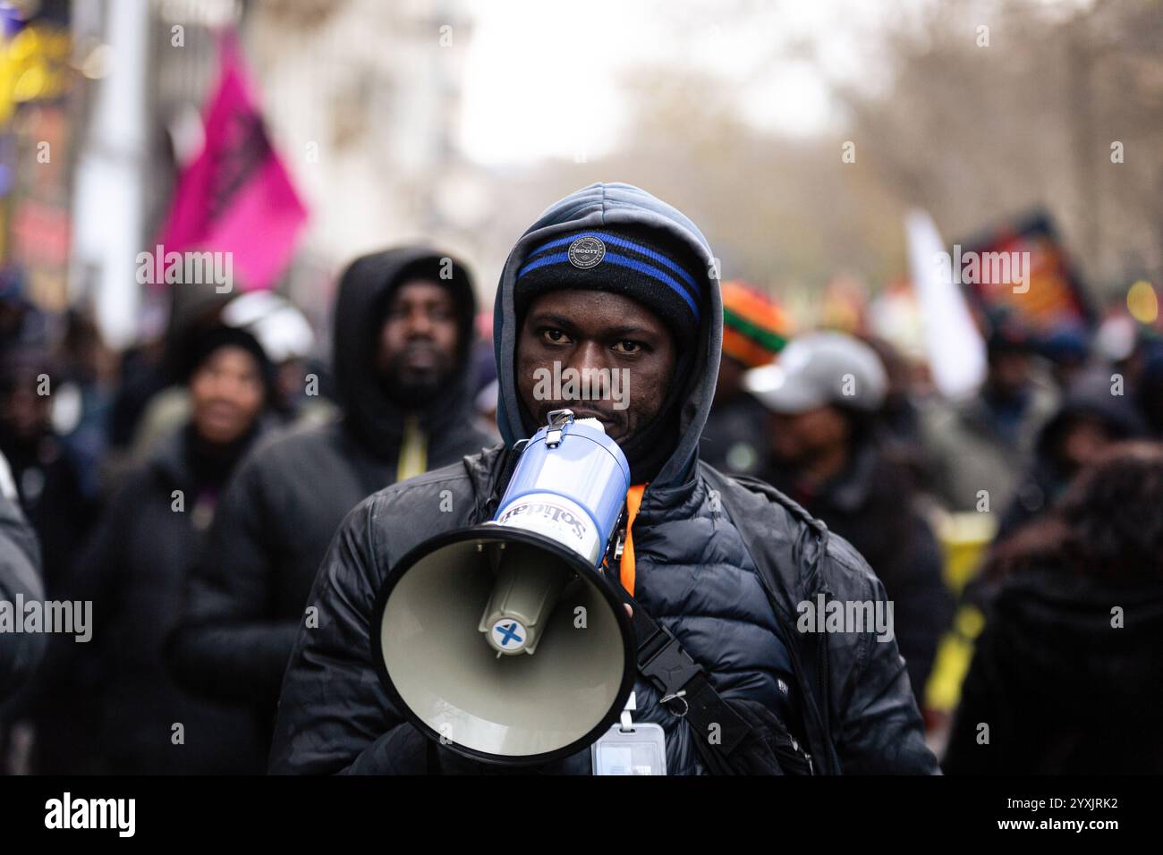 Paris, Frankreich. Dezember 2024. Ein Wanderarbeiter singt während der Demonstration Slogans auf einem Megaphon zur Unterstützung der Migranten ohne Papiere. Hunderte von Menschen demonstrierten in Paris gegen die französische Migrationspolitik. Mehrere Gewerkschaften und Verbände haben sich der Aktion angeschlossen, um Migranten ohne Papiere sowie diejenigen zu unterstützen, die regularisiert sind, aber gleichermaßen von der französischen Bürokratie betroffen sind. Quelle: SOPA Images Limited/Alamy Live News Stockfoto