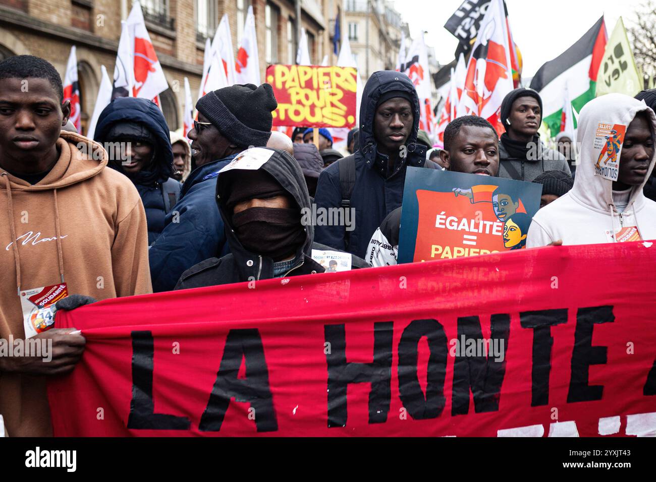 Paris, Frankreich. Dezember 2024. Migranten halten während der Demonstration zur Unterstützung der nicht dokumentierten Migranten ein Banner mit der Aufschrift „die Schande“. Hunderte von Menschen demonstrierten in Paris gegen die französische Migrationspolitik. Mehrere Gewerkschaften und Verbände haben sich der Aktion angeschlossen, um Migranten ohne Papiere sowie diejenigen zu unterstützen, die regularisiert sind, aber gleichermaßen von der französischen Bürokratie betroffen sind. (Foto: Telmo Pinto/SOPA Images/SIPA USA) Credit: SIPA USA/Alamy Live News Stockfoto