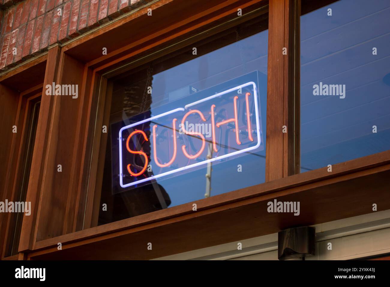 Blick auf ein Neon-Sushi-Schild im Fenster eines Restaurants. Stockfoto