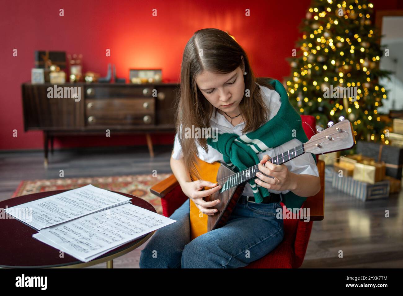 Die fleißige Musikerin schärft die Balalaika-Fähigkeiten mit Notizen und bereitet sich auf das Weihnachtskonzert vor Stockfoto