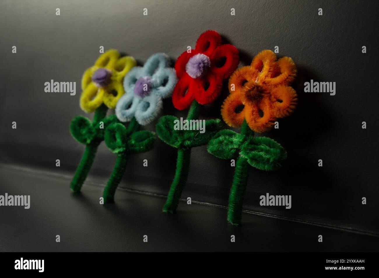 Selektive Winkelansicht schöne bunte handgemachte Rohr Reiniger Blumenhandwerk, Sonnenblumenhandwerk Schlüsselanhänger, dunkler über schwarzem Hintergrund Stockfoto