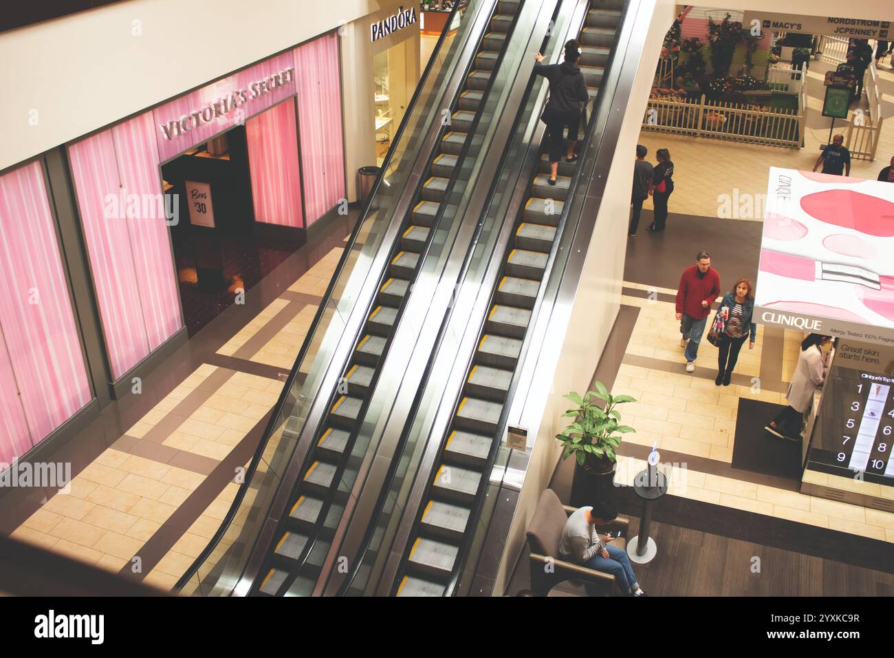 Brea, Kalifornien, USA - 04-06-2019: Ein Blick auf Käufer, die auf einer Rolltreppe zwischen Ladenfronten in einem Einkaufszentrum fahren. Stockfoto