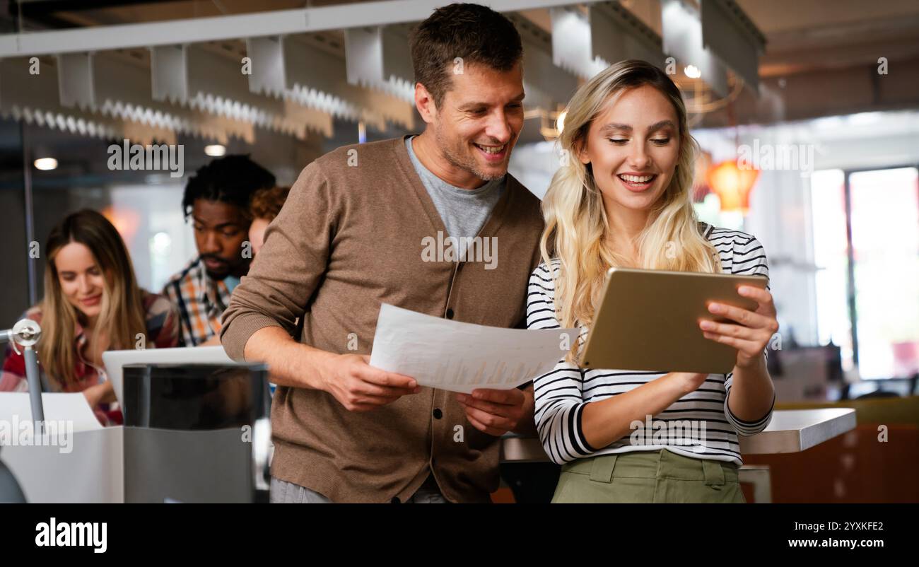 Lächelnd treffen sich verschiedene Kollegen in einem Brainstorming in der Vorstandsetage, um gemeinsam Finanzstatistiken zu diskutieren Stockfoto