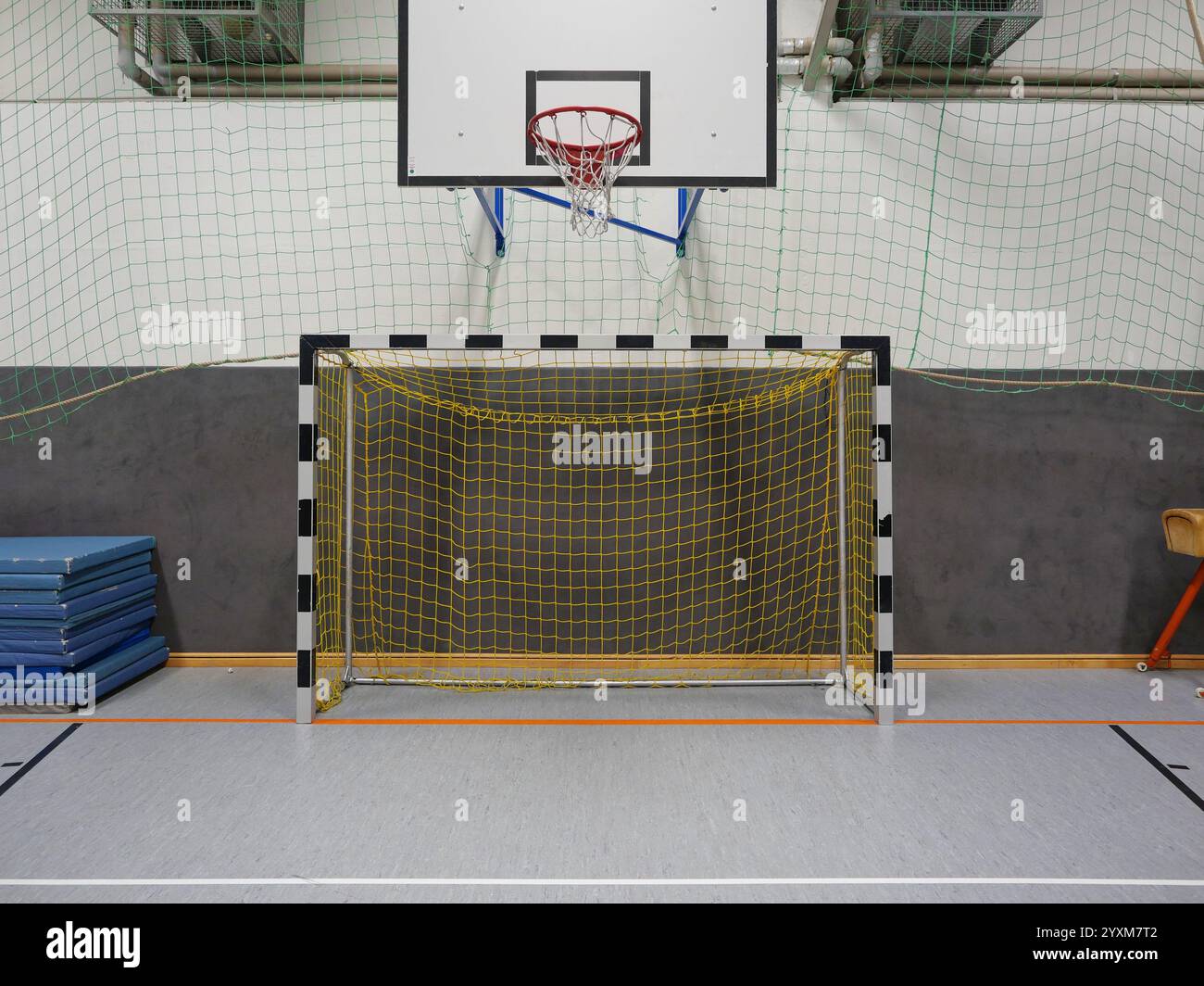 Fußballtor mit gelbem Netz, Basketballkorb und Gymnastikausrüstung wie Matten und Gewölbepferd in nostalgischer Atmosphäre. Stockfoto