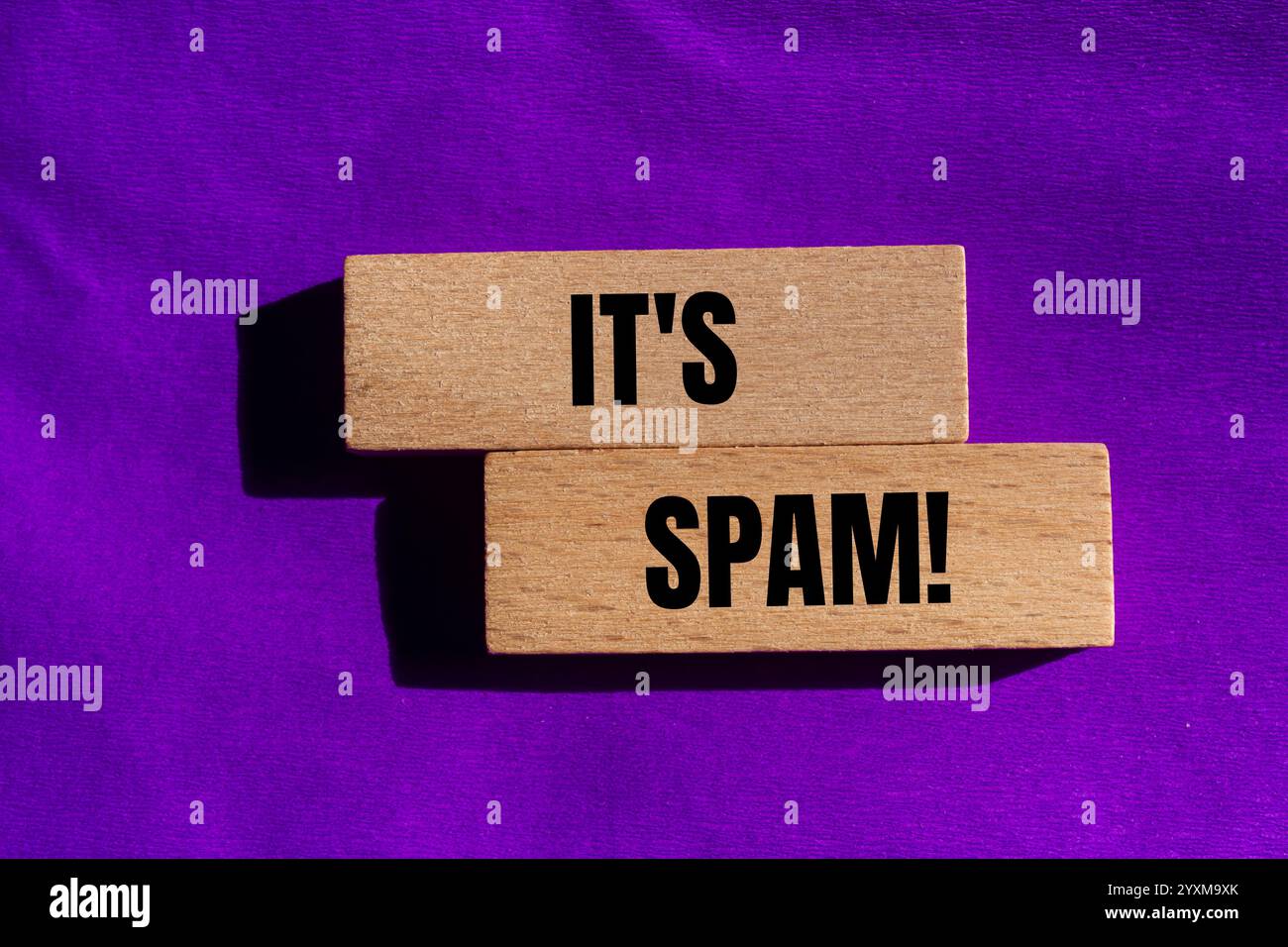 Es ist eine Spam-Nachricht auf Holzblöcken mit violettem Hintergrund. Konzeptionell ist das Spam-Symbol. Kopierbereich. Stockfoto