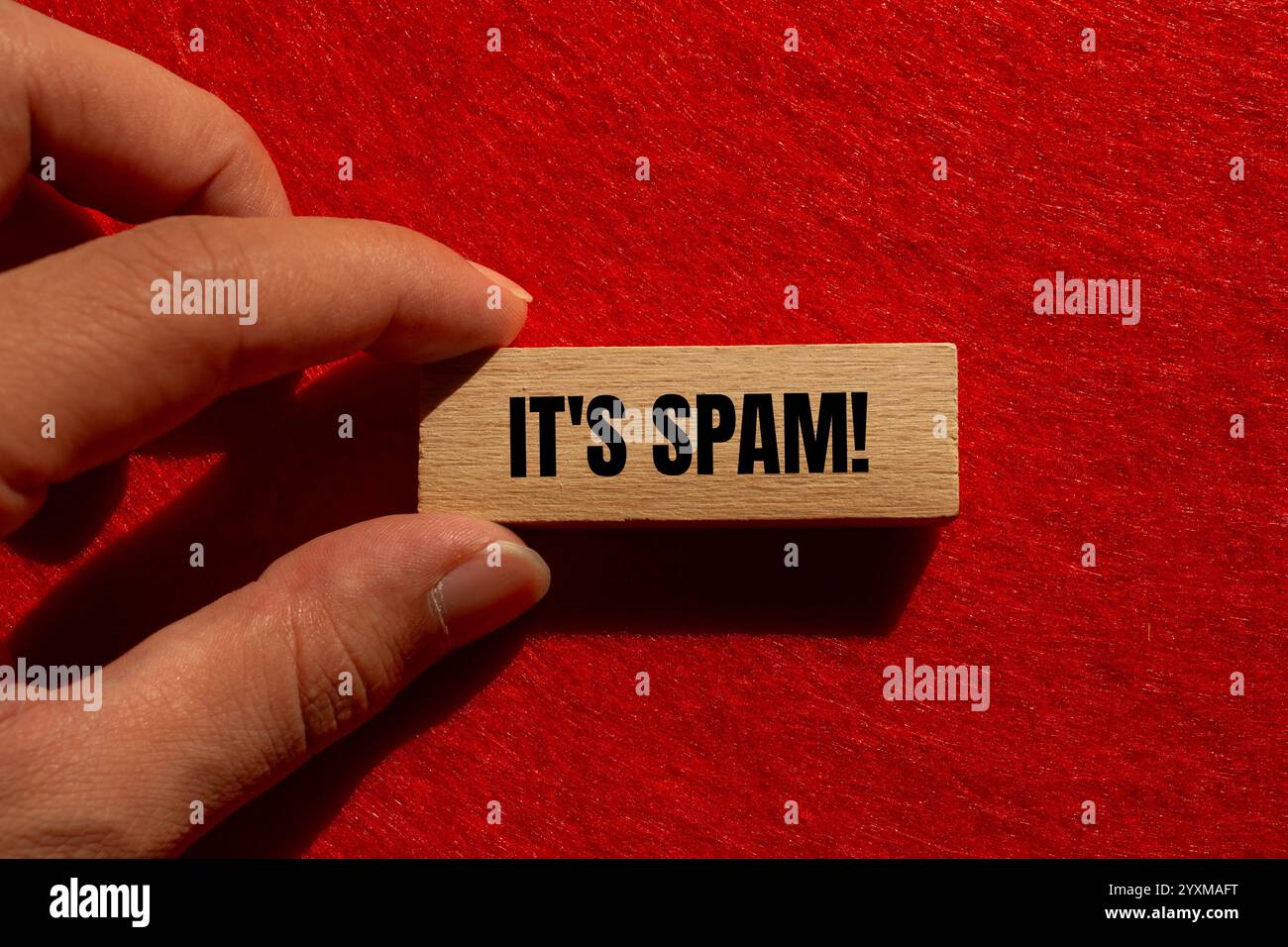 Es ist eine Spam-Nachricht auf Holzblock mit rotem Hintergrund. Konzeptionell ist das Spam-Symbol. Kopierbereich. Stockfoto