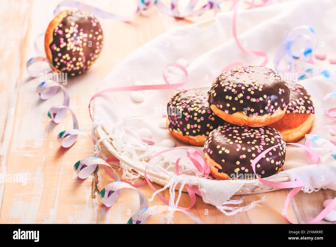 Gefüllte Berliner, deutsche Donuts für Party, Karneval, Geburtstagsfeier mit Streamers Stockfoto