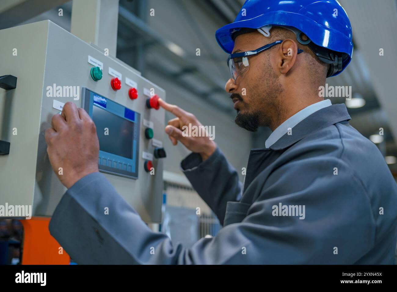 Afroamerikanischer Profi, ein Fabrikingenieur, der die industrielle Schalttafel aktualisiert. Moderne Industrie, Menschen und Automatisierungskonzepte. Stockfoto