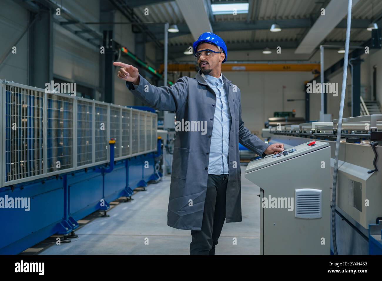 Afroamerikanischer Profi, ein Fabrikingenieur, der die industrielle Schalttafel aktualisiert. Moderne Industrie, Menschen und Automatisierungskonzepte. Stockfoto