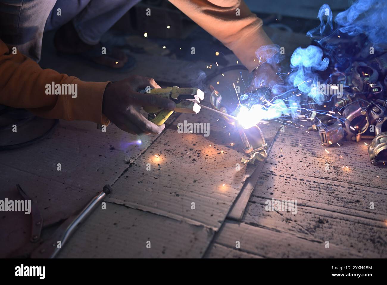 Der Bauarbeiter führt Schweißarbeiten mit den brennenden Funken durch. Stockfoto