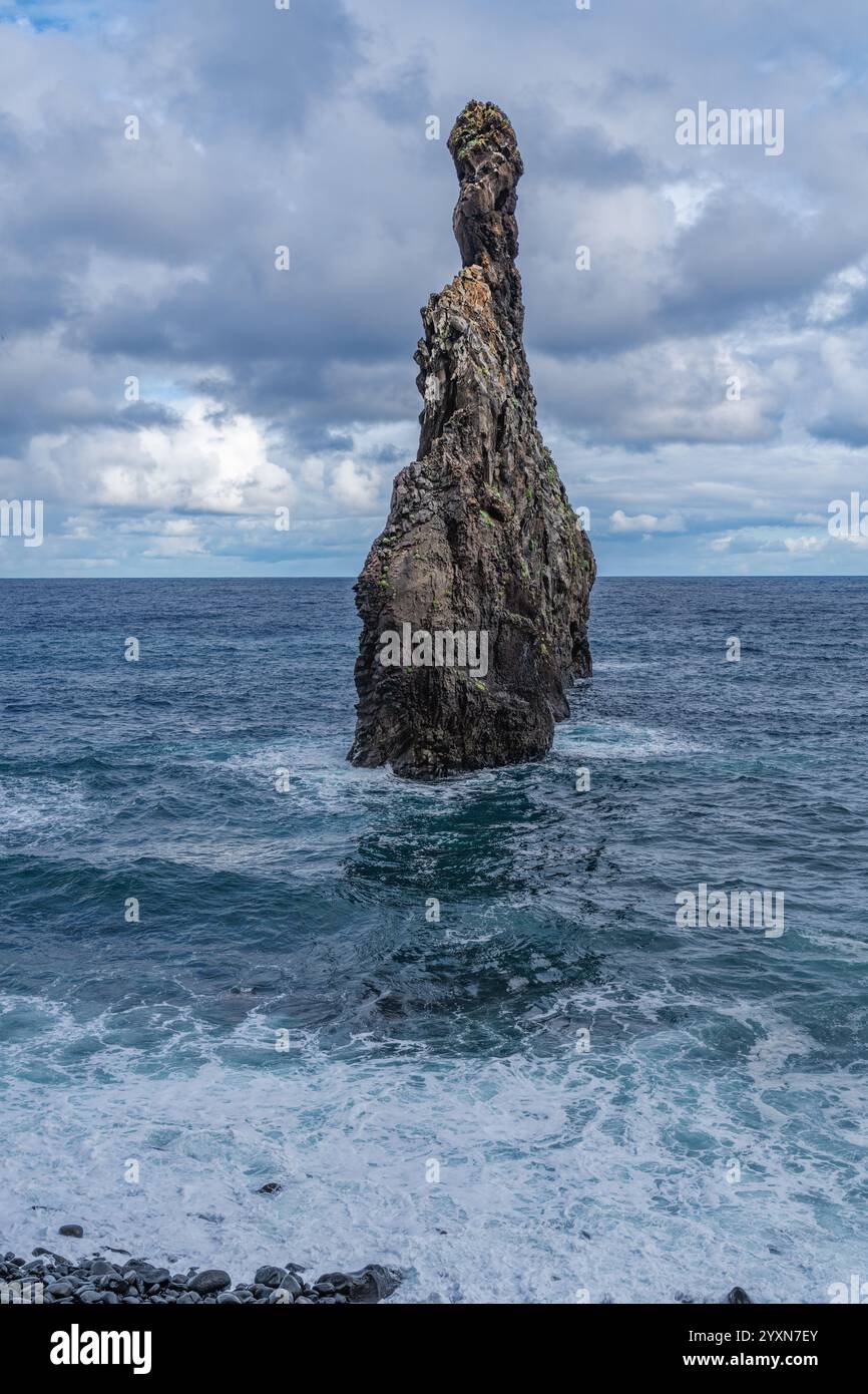 Ein atemberaubender Blick auf zerklüftete Felsformationen im Ozean, umgeben von Wellen und einem bewölkten Himmel. Die Kontraste der natürlichen Texturen wecken Wunder und Ruhe Stockfoto