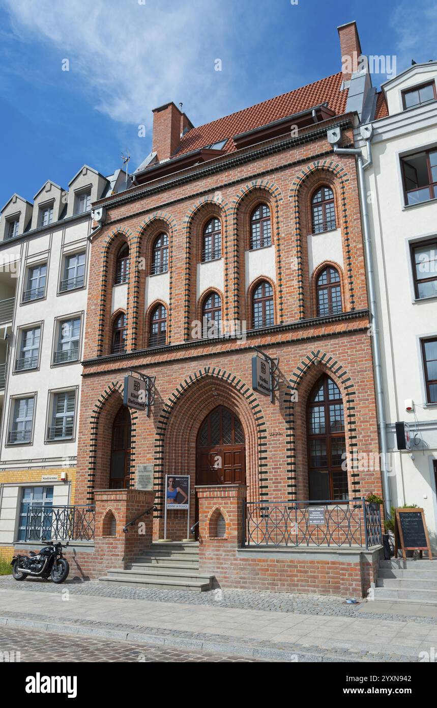 Historisches Backsteingebäude mit hohen Fenstern neben modernen Gebäuden unter blauem Himmel, Elblag, Elbing, Warminsko-Mazurskie, Woiwodschaft Ermland-Masuren Stockfoto