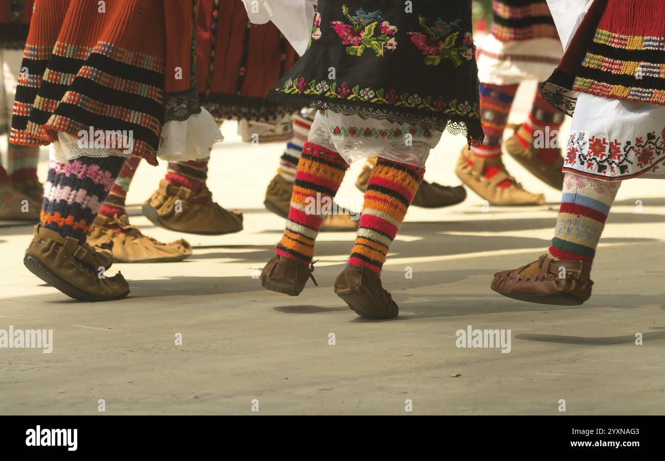 Bulgarische Folklore. Mädchen tanzen Volkstanz. Menschen in traditionellen Kostümen tanzen bulgarische Volkstänze. Nahaufnahme der weiblichen Beine mit traditionellem Sho Stockfoto