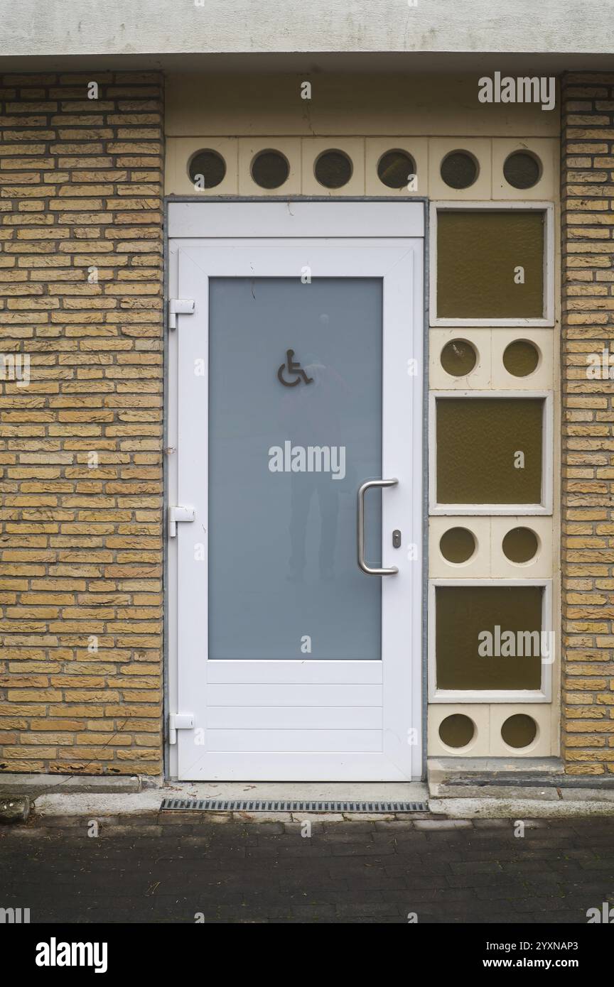 Tür für öffentliche Toiletten mit barrierefreiem Schild für Behinderte mit Milchglas und weißem Rahmen Stockfoto